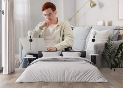 Young man in wheelchair using laptop at home Wall mural