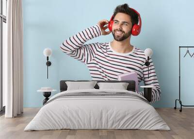 Young man listening to audiobook on light background Wall mural