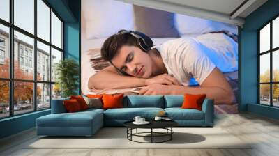 Young man listening to music in bedroom at home Wall mural