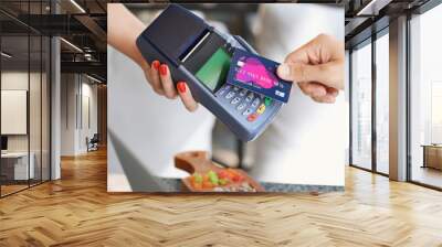 Young man paying by credit card in cafe, closeup Wall mural