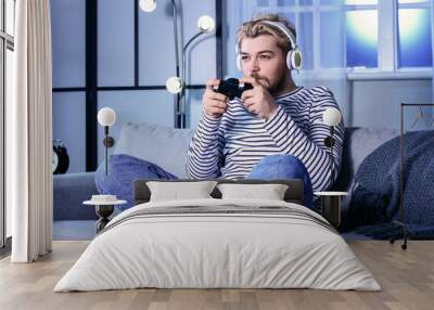 Young man playing video game at home late in evening. Concept of addiction Wall mural