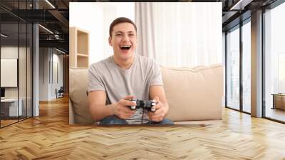 Young man playing video games at home Wall mural