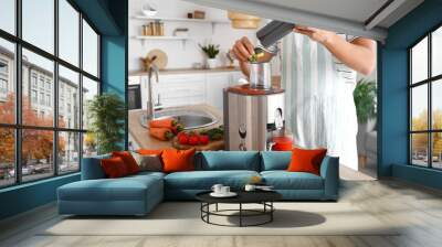 Young man preparing healthy vegetable juice in kitchen Wall mural