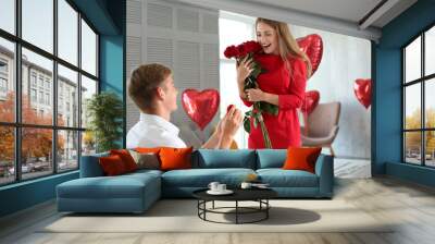 Young man proposing to his beloved with beautiful engagement ring at home Wall mural