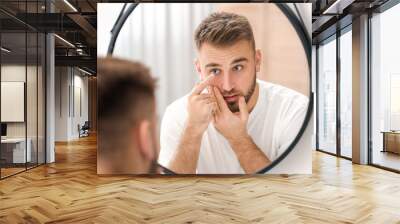 Young man putting in contact lenses near mirror Wall mural