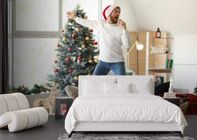 Young man singing with microphone at home on Christmas eve Wall mural