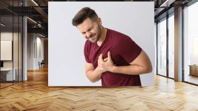 Young man suffering from heart attack on light background Wall mural