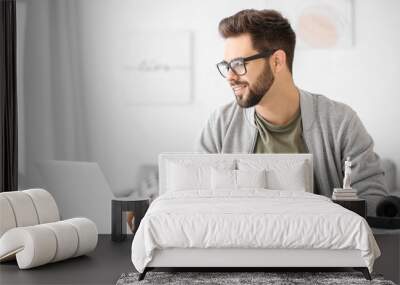 Young man using laptop for online learning at home Wall mural