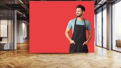 Young man wearing apron on color background Wall mural