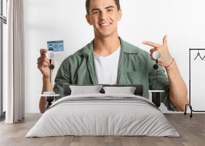 Young man with driving license on white background Wall mural