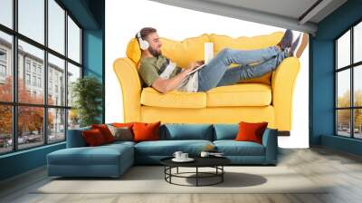 Young man with headphones and laptop on sofa against white background Wall mural