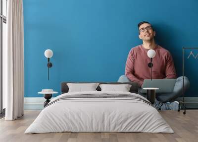 Young man with laptop sitting near color wall Wall mural