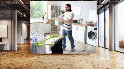 Young man with laundry basket at home Wall mural