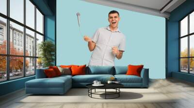 Young man with microphone on blue background Wall mural