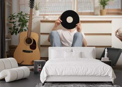 Young man with vinyl disks and record player listening to music at home Wall mural