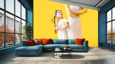 Young mother and daughter with kitchen utensils on color background Wall mural