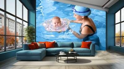 Young mother and her adorable baby with inflatable ring in swimming pool Wall mural