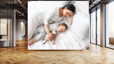 Young mother and her adorable baby with toy sleeping on bed Wall mural