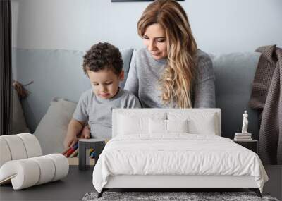 Young mother with cute little son playing with abacus at home Wall mural