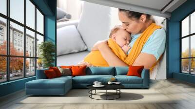 Young mother with little baby in sling at home Wall mural