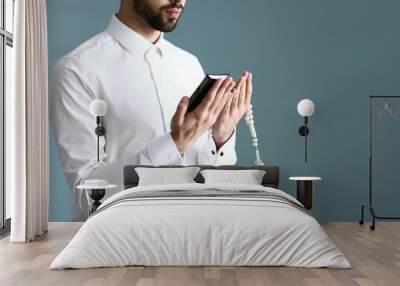 Young Muslim man praying against color background Wall mural