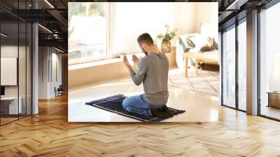 Young Muslim man praying at home Wall mural