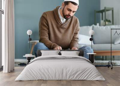 Young Muslim man praying indoors Wall mural