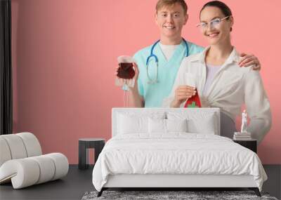 Young pregnant woman with paper drop and nurse holding blood pack for transfusion on pink background Wall mural