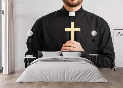 Young priest praying to God on light background Wall mural