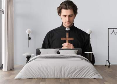 Young priest praying with cross on dark background Wall mural