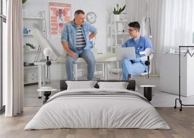 Young urologist working with laptop and patient in office Wall mural