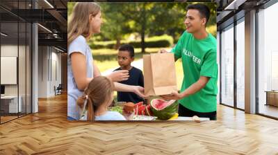 Young volunteer giving food to poor people outdoors Wall mural