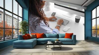 Young web designer working with computer at table in office Wall mural