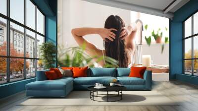 Young woman applying coconut oil onto her hair in bathroom Wall mural