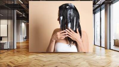 Young woman applying hair mask on beige background, closeup Wall mural