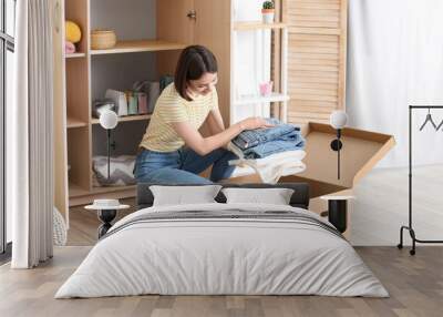 Young woman arranging clothes at wardrobe Wall mural