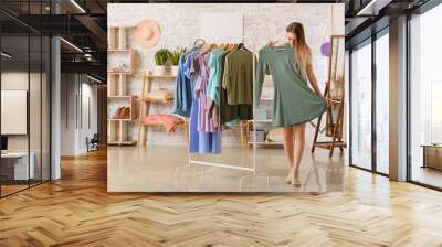 Young woman choosing clothes in dressing room Wall mural