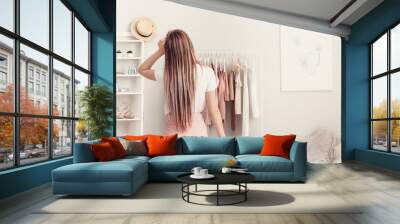 Young woman choosing clothes in her dressing room, back view Wall mural