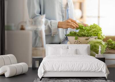 Young woman cooking fresh salad in kitchen Wall mural