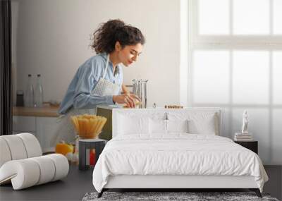 Young woman cooking in kitchen Wall mural