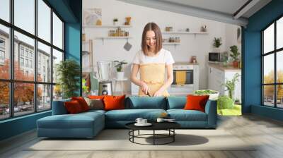 Young woman cutting apple in kitchen Wall mural