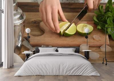 Young woman cutting lime for mojito in kitchen Wall mural