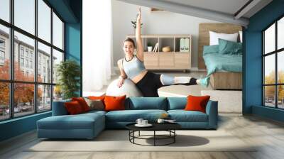 Young woman doing exercise with fitball at home Wall mural