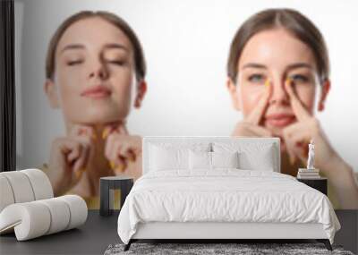 Young woman doing face building exercises against white background Wall mural