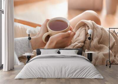 Young woman drinking hot tea at home, closeup Wall mural