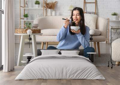 Young woman eating tasty cereal rings at home Wall mural