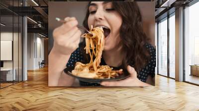 Young woman eating tasty pasta in cafe Wall mural