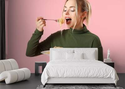 Young woman eating tasty pasta on pink background Wall mural