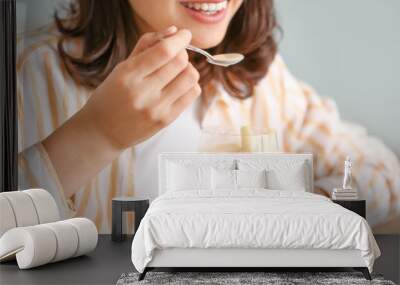 Young woman eating tasty yogurt at home, closeup Wall mural