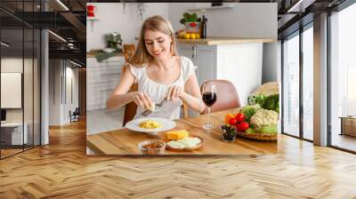 Young woman grating cheese on tasty pasta in kitchen Wall mural